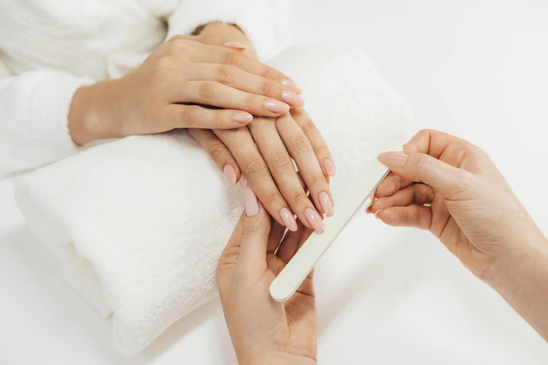 A technician filing a client's nails during a manicure