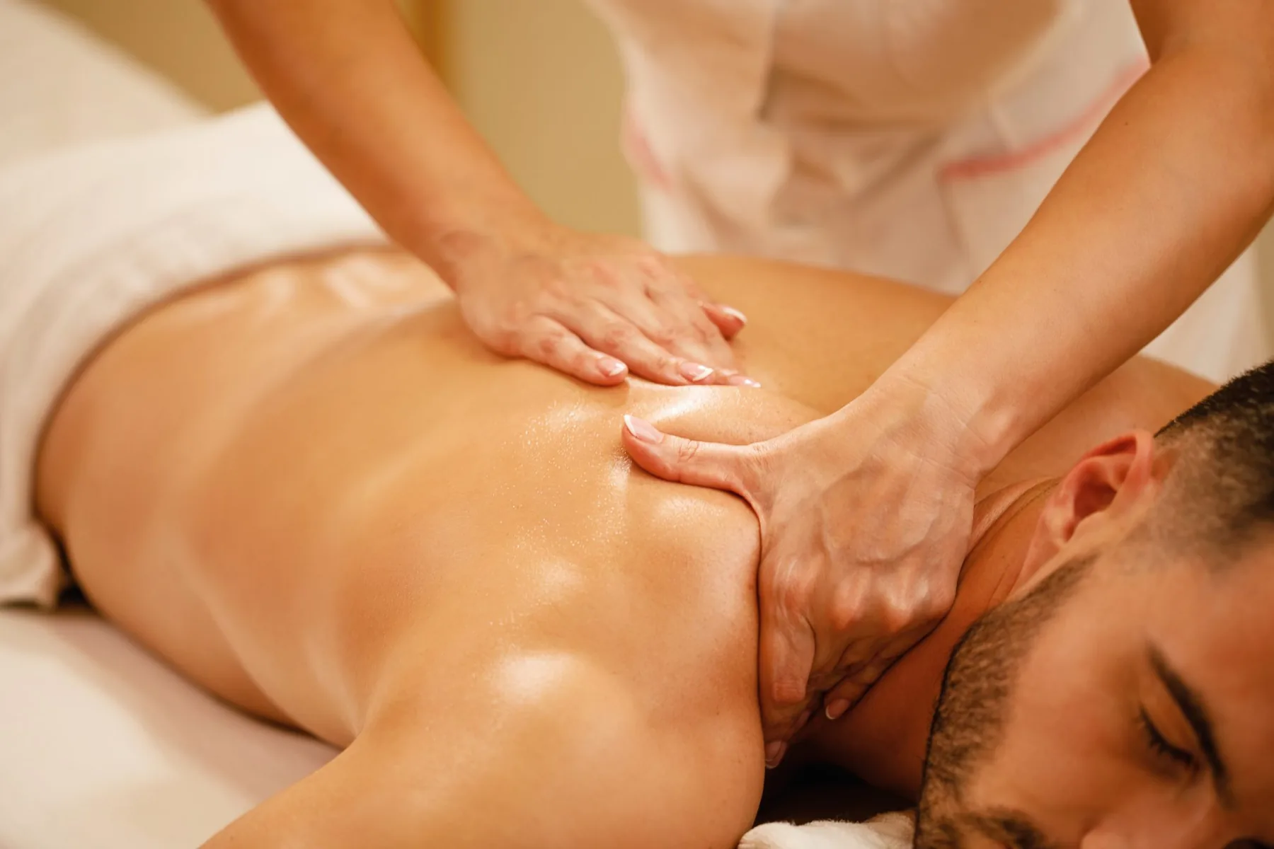 A therapist giving a back massage in a warmly lit treatment room